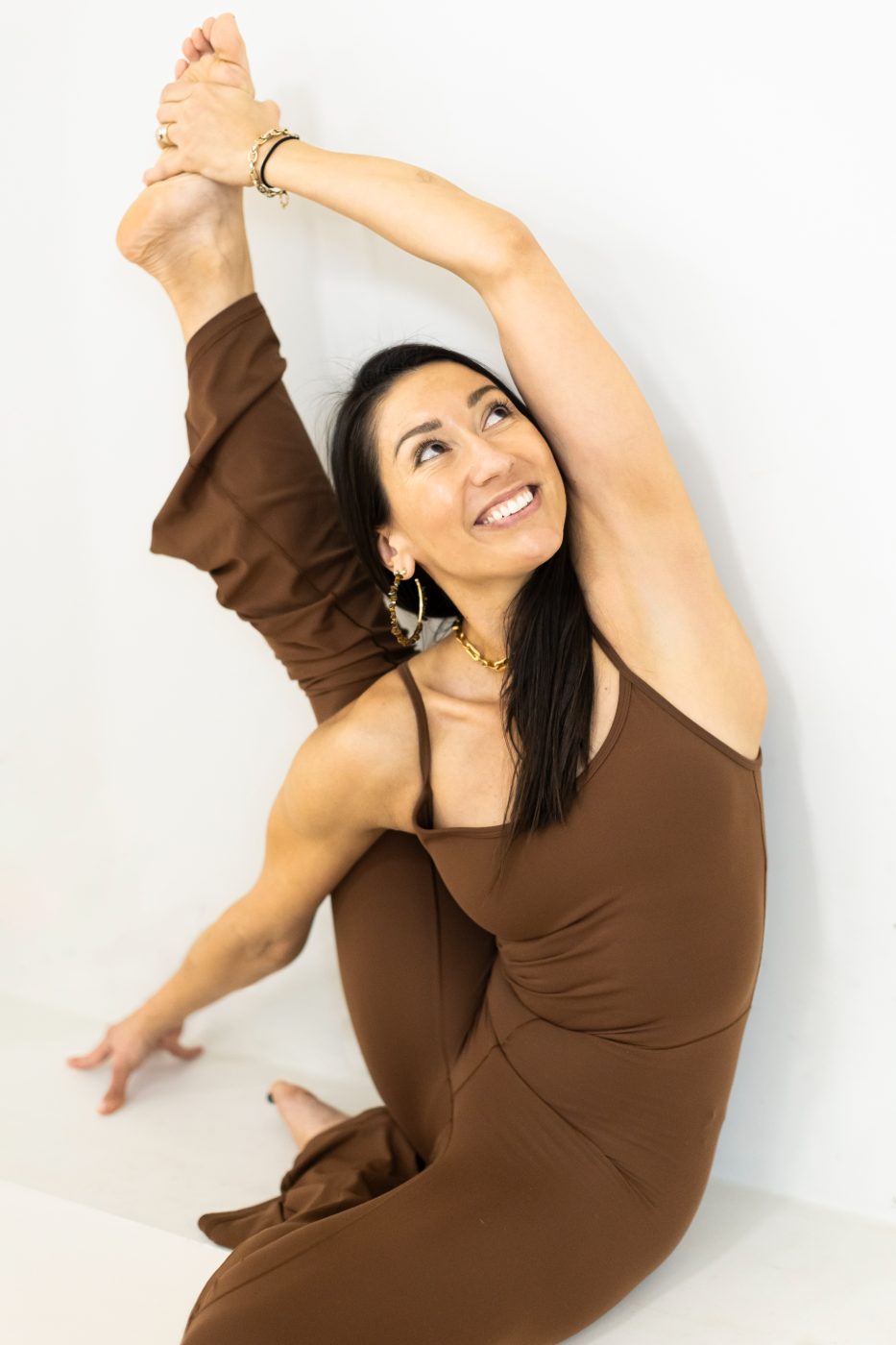 An instructor smiling mid-stretch under the studio arch